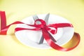 Plate with spoon, knife and fork tied with red ribbon Royalty Free Stock Photo