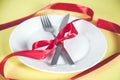 Plate with spoon, knife and fork tied with red ribbon Royalty Free Stock Photo