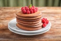 Plate with stack of tasty chocolate pancakes and raspberries on wooden table Royalty Free Stock Photo