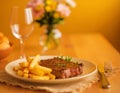 a plate with a steak and French fries on the dining table Royalty Free Stock Photo