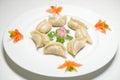 A plate of steamed dumplings, jiaozi decorated with vegetable and tomatoes