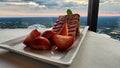 A plate of strawberry short cake with sliced strawberries on a table with a white tablecloth and a gorgeous view of the city Royalty Free Stock Photo