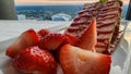 A plate of strawberry short cake with sliced strawberries on a table with a white tablecloth and a gorgeous view Royalty Free Stock Photo