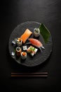 a plate of sushi and chopsticks on a black surface with a green leaf on top of the plate and chopsti Royalty Free Stock Photo