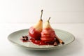 Plate with sweet pears stewed in red wine on white table