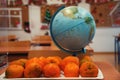 Plate of tangerines and model globe on the bench