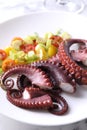 Plate with tasty boiled octopus tentacles and salad on light table, closeup Royalty Free Stock Photo
