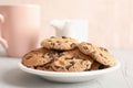 Plate with tasty chocolate chip cookies and blurred cup of milk on gray background Royalty Free Stock Photo