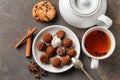 Plate with tasty chocolate truffles and cup of tea on grey table Royalty Free Stock Photo