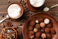 Plate with tasty chocolate truffles and cups of cappuccino on wooden table Royalty Free Stock Photo