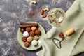 Plate with tasty chocolate truffles and glass of wine on grey table