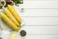 Plate with tasty cooked corn cobs on white wooden table, flat lay. Space for text Royalty Free Stock Photo