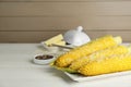 Plate with tasty cooked corn cobs on white wooden table, space for text Royalty Free Stock Photo