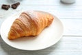 Plate with tasty croissant on white table, closeup. French pastry