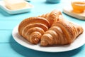 Plate with tasty croissants on light blue table, closeup. French pastry