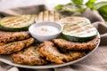 Plate with tasty grilled zucchini, vegetable pancakes and sour cream on napkin, closeup