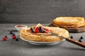 Plate with tasty pancakes, chocolate and berries on dark table