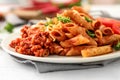 Plate with tasty penne pasta and bolognese sauce on table, closeup