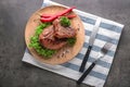 Plate with tasty steaks, herbs, chili and spices on grey table Royalty Free Stock Photo