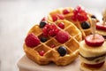 Plate with tasty waffles, fruit, and berries on grey background