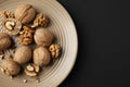 Plate with tasty walnuts on dark background Royalty Free Stock Photo