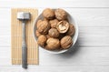 Plate with tasty walnuts and hammer on white wooden table Royalty Free Stock Photo