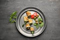 Plate with tasty zucchini rolls, green olives and tomatoes on grey table