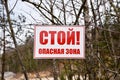 A plate with the text in Russian: Stop! Exclusion zone! Banner on barbed wire in dangerous and protected area. Stop forbidden sign Royalty Free Stock Photo