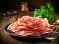 plate with thinly sliced ham on wooden table