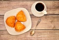 A plate with three curd buns and a cup of black coffee on a saucer, stand on a wooden table Royalty Free Stock Photo