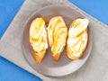 Plate with three delicious French toast with bananas, pears, cream cheese, caramel syrup, top view, blue table. Royalty Free Stock Photo