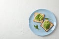 Plate with toasts with avocado, arugula and sesame on background, top view