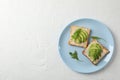 Plate with toasts with avocado, arugula and sesame on white background