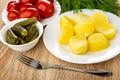 Plate with tomatoes, dill, bowl with gherkins, plate with pieces of baked potato, fork on table Royalty Free Stock Photo