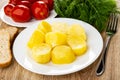 Plate with tomatoes, dill, pieces of bread, plate with baked potato, fork on wooden table Royalty Free Stock Photo