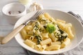 Plate with tortelloni with spinach and broccoli, fork, napkin on a light background