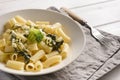 Plate with tortilloni with sauce and spinach and cheese, broccoli, fork, napkin on a light background, spinach paste