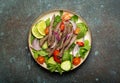 Plate with traditional Thai beef salad with vegetables and mint top view served on rustic concrete stone background