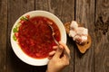 a plate with traditional Ukrainian borscht and a piece of bread with bacon on a side wooden table