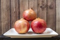 Plate with trio of ripe pomegranates and dark wooden