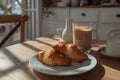 A plate with two croissants and a glass of coffee on a wooden table