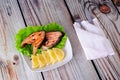 A plate with two steaks of pink salmon, lemon and salad on the table, next to a fork, knife and napkin Royalty Free Stock Photo
