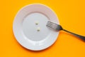 On the plate are two tablets and a fork, orange background