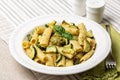 Plate of vegan tubular pasta dish, pistachio pesto rigatoni with zucchini.