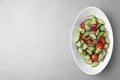 Plate of vegetarian salad with cucumber, tomato and onion on light background. Space for text