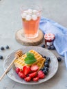 Plate of waffles decorated with honey and fresh berries and Glass of fresh red fruit juice on gray stone background. Food concept Royalty Free Stock Photo