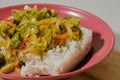 A plate of white rice with sauteed gambas and sliced onions on a wooden cutting board