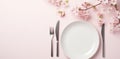 plate on white table, pink flowers, fork and knife Royalty Free Stock Photo