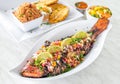 Plate of whole grilled fish with vegetables and lemon pieces on top Royalty Free Stock Photo