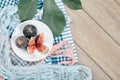 A plate of whole and sliced black figs, a leaf and blue and pink tablecloths on wooden table